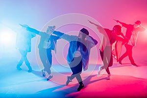 Diverse group of people dancing in studio with red and blue dual color light