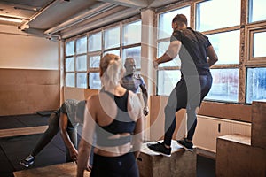 Diverse group of people doing box jumps during a workout