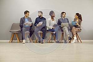 Diverse group of people talking while sitting in office and waiting for job interview