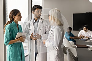 Diverse group of practitioners in uniform coats discussing medical profession