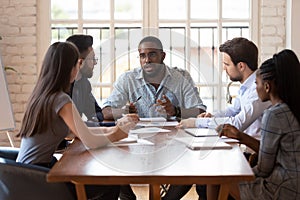 Diverse group of professionals listening to african american team leader.