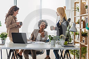 Diverse group of smiling business women having a break in office talking