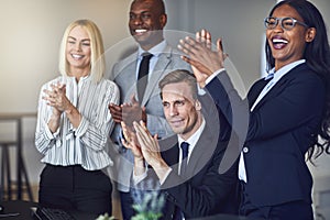 Diverse group of smiling businesspeople clapping after an office