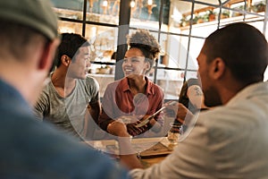 Smiling young friends talking together over a bistro dinner