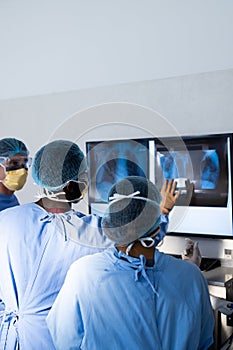 Diverse group of surgeons discussing x rays on screen in operating theatre, copy space