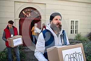 Diverse group of volunteers with donation boxes standing outdoors, social care and charity concept