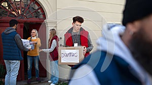 Diverse group of volunteers with donation boxes standing outdoors, social care and charity concept