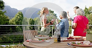 Diverse group of women enjoy a meal outdoors, with a mountainous backdrop