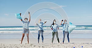 Diverse group of women wearing volunteer t shirts and face masks picking up rubbish from beach