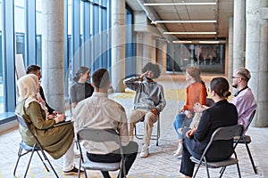 A diverse group of young business entrepreneurs gathered in a circle for a meeting, discussing corporate challenges and