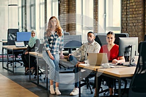 A diverse group of young business individuals congregates in a modern startup coworking center, embodying collaborative