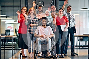 A diverse group of young business people walking a corridor in the glass-enclosed office of a modern startup, including