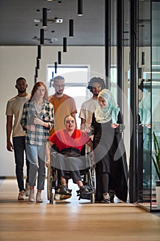A diverse group of young business people walking a corridor in the glass-enclosed office of a modern startup, including