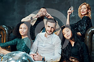 Diverse group of young friends hang out and drink champagne at night club