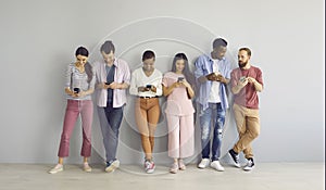 Diverse group of young people using smartphones, text messaging and watching videos