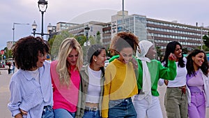 Diverse group of young women friends walking together at city street.