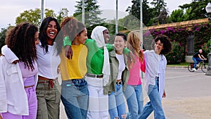 Diverse group of young women friends walking together at city street.