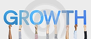 Diverse hands holding up blue letters forming the word growth