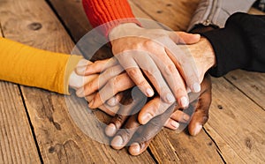 Diverse hands are join together on the wooden table