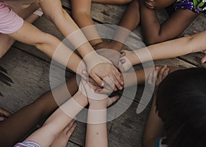 Diverse hands are join together on the wooden table