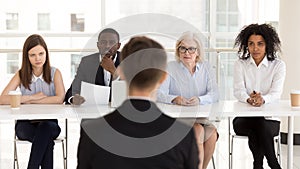 Diverse HR managers listen to applicant answering questions rear view