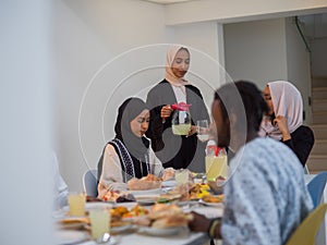 A diverse Islamic family gathers for iftar, joyfully breaking their fast together during Ramadan, with a Muslim woman in photo