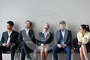 Diverse job candidates sitting waiting in queue for interview