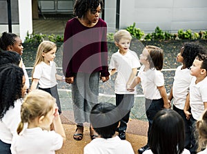 Diverse kindergarten students standing holding hands together