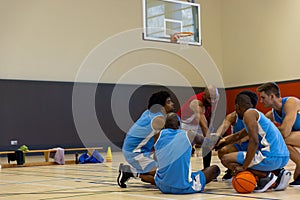 Diverse male basketball players teaming up with coach at gym, copy space