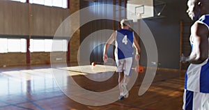 Diverse male basketball team and coach practice dribbling ball