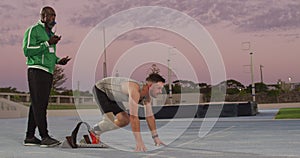 Diverse male coach and disabled athlete with running blade training at sunset