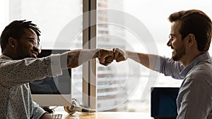 Diverse male colleagues giving fist bump at workplace