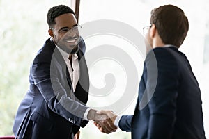 Diverse male colleagues handshake get acquainted at meeting