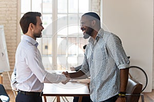 Diverse male employees handshake at office meeting