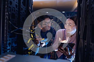 Diverse male and female engineers with digital tablet inspecting the server in computer server room