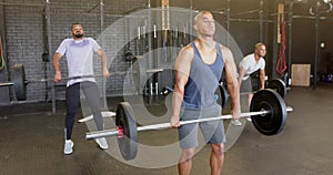 Diverse male group lifting barbells, free weight training at gym, in slow motion