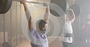 Diverse male group lifting barbells, free weight training at gym, in slow motion