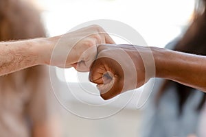 Diverse male hands giving fist bump, close up view