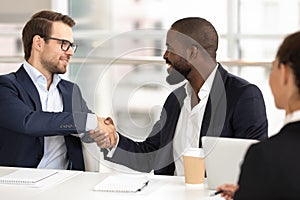 Diverse male partners handshake closing deal at meeting