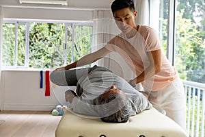 Diverse male physiotherapist advising and senior male patient stretching