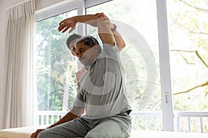 Diverse male physiotherapist advising and senior male patient stretching arm