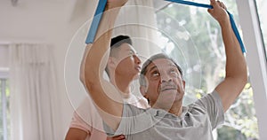 Diverse male physiotherapist advising and senior male patient using exercise band, in slow motion