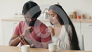 Diverse man and woman use digital tablet pc multiracial arabian muslim couple looking at device screen shopping in