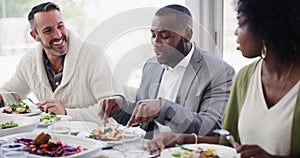 Diverse and mature group of friends eating, talking and having dinner around a table at home or at a luxury hotel