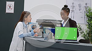 Diverse medical team working with greenscreen on laptop