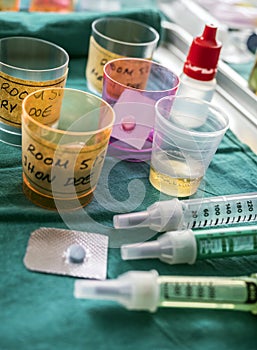 Diverse medication in glasses monodose along with insulin injectors in hospital, conceptual image