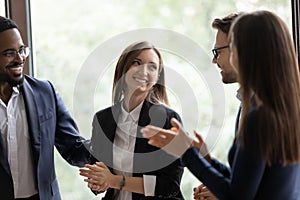 Diverse millennial colleagues meeting new female teammate in office