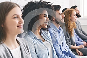 Diverse millennial group sitting in row, waiting for something