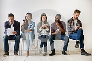 Diverse millennial people waiting in queue holding resumes using