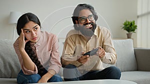 Diverse multiethnic couple at home bored angry arabian woman offend on husband addicted playing console video game with photo